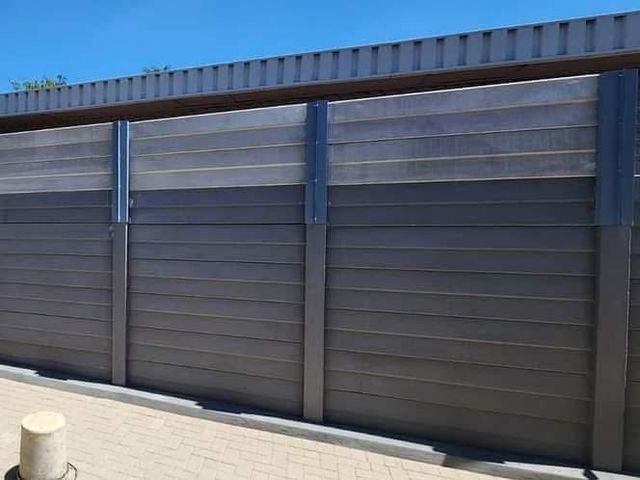A standard precast wall that has been extended by two panels to increase its height for better security.