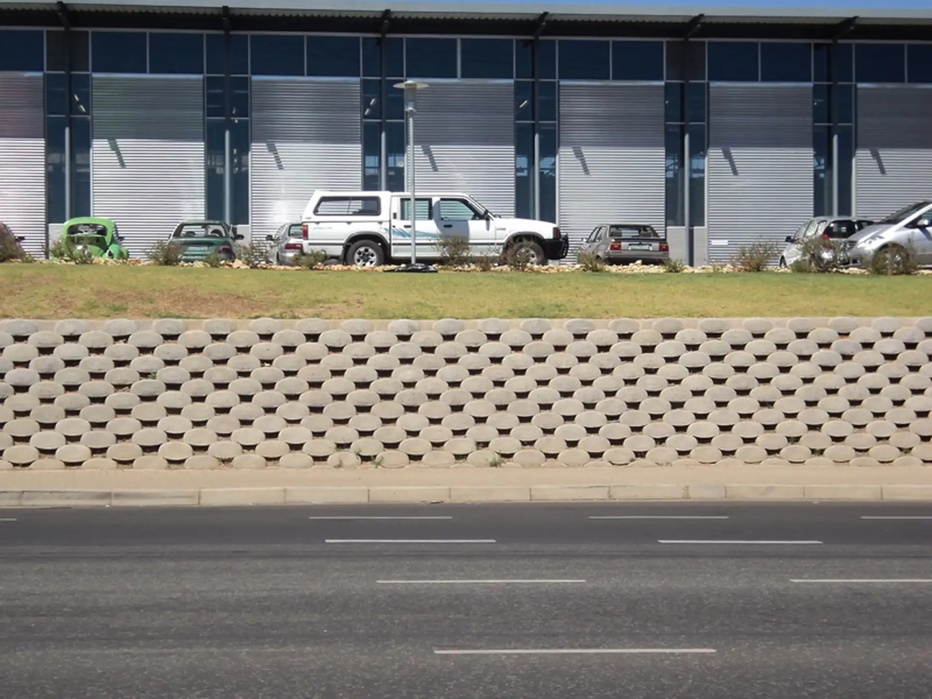 A large, curved Loffelstein retaining wall with lush green plants.
