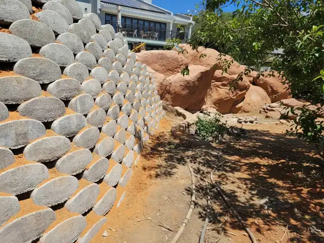 A close-up of a Loffelstein wall with mature plants growing out of it.