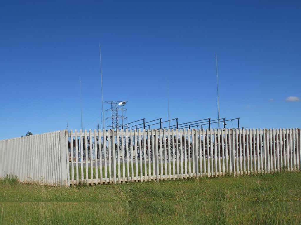 A close-up view of a concrete palisade fence showing the spacing and robust construction.